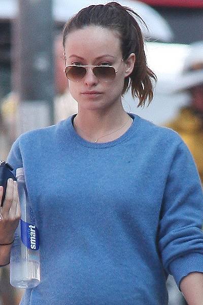 Make up free Olivia Wilde shows off her baby bump in a blue sweater, black tights and flip flops as she leaves the gym in West Hollywood, CA
