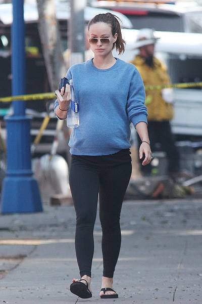 Make up free Olivia Wilde shows off her baby bump in a blue sweater, black tights and flip flops as she leaves the gym in West Hollywood, CA