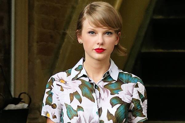 Singer Taylor Swift, wearing a floral romper with leather belt and Gucci suede yellow pumps with a Dolce & Gabbana tote, leaves ModelFit Gym in SoHo on July 2, 2014 in New York City. Taylor pauses to say hello to a man in a wheelchair