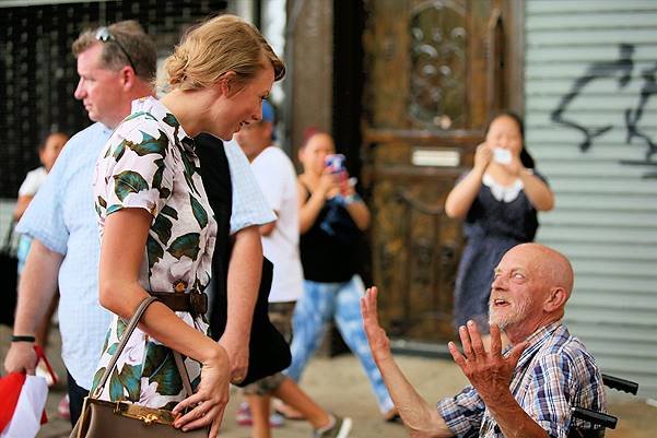 Singer Taylor Swift, wearing a floral romper with leather belt and Gucci suede yellow pumps with a Dolce & Gabbana tote, leaves ModelFit Gym in SoHo on July 2, 2014 in New York City. Taylor pauses to say hello to a man in a wheelchair